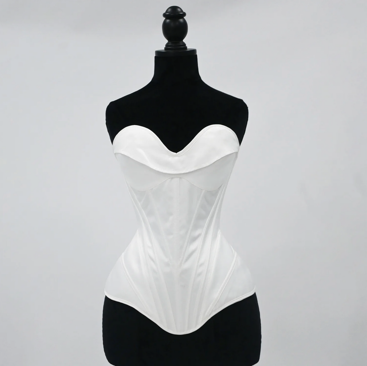White satin bridal corset bustier with structured boning and a sweetheart neckline on a black mannequin.