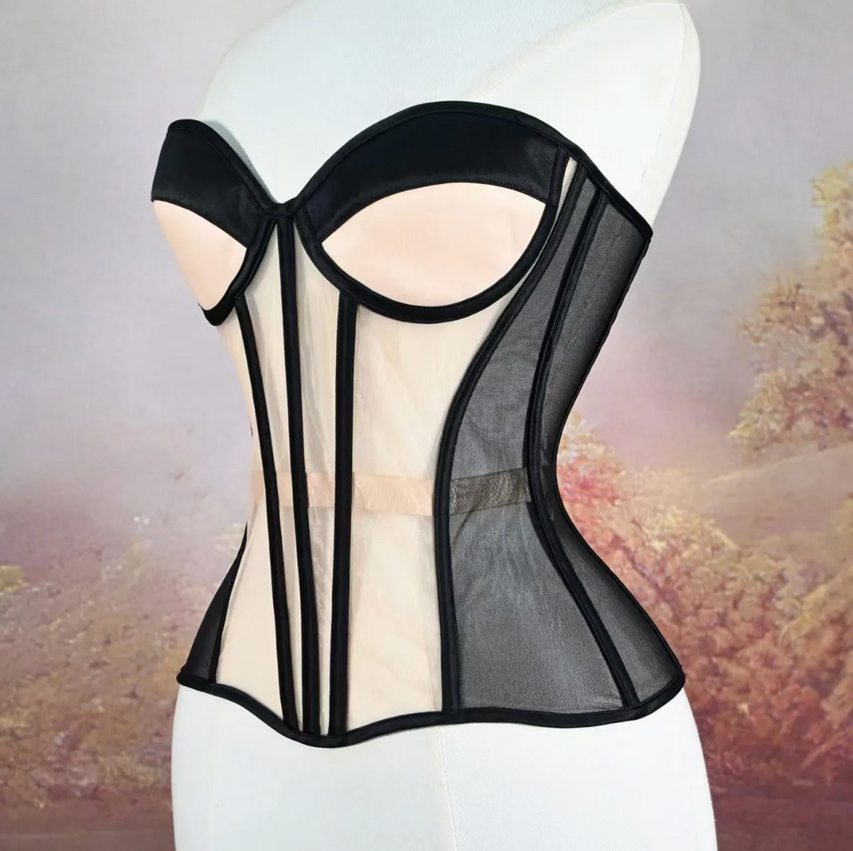 Handmade black and nude mesh strapless corset with structured boning and architectural paneling on a mannequin.