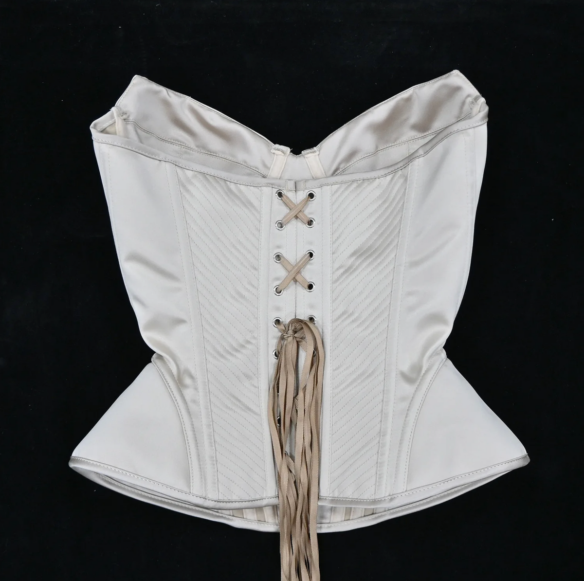 Cream-colored luxury corset bustier with structured boning, diagonal stitching, and a classic lace-up front closure.