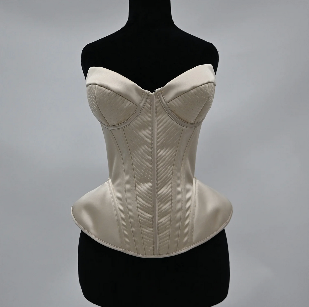 Cream-colored satin corset bustier with structured boning, sweetheart neckline, and elegant quilted chevron detailing.