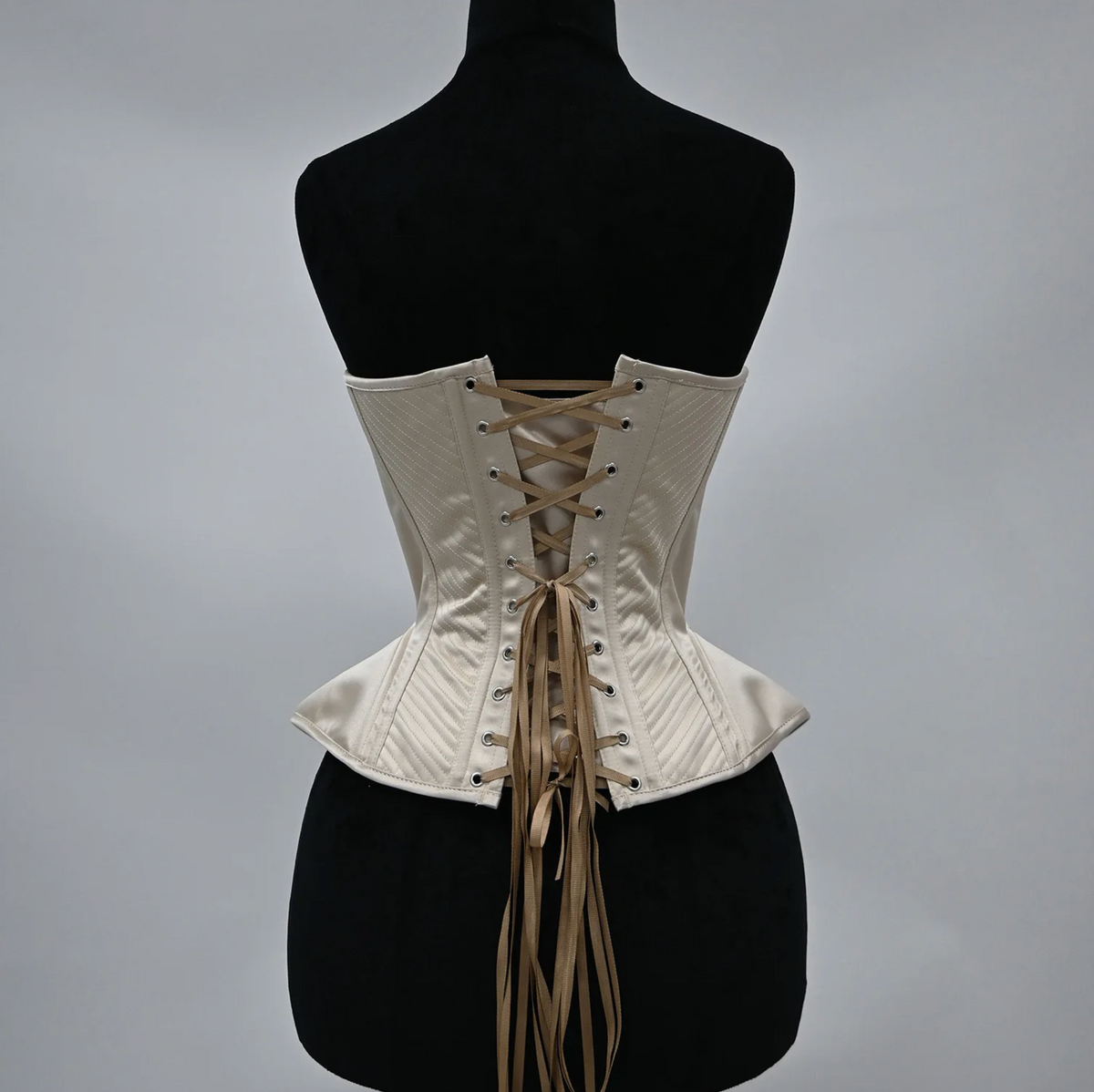 Cream-colored handmade corset bustier with structured boning, intricate stitching, and a classic lace-up back closure.