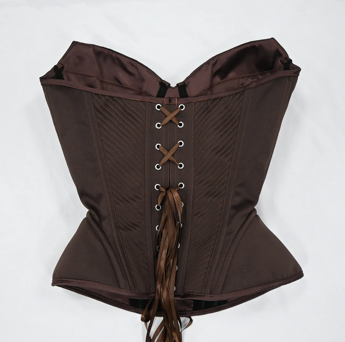 Dark brown satin corset bustier with structured boning, diagonal stitching, and a matching ribbon lace-up back closure.