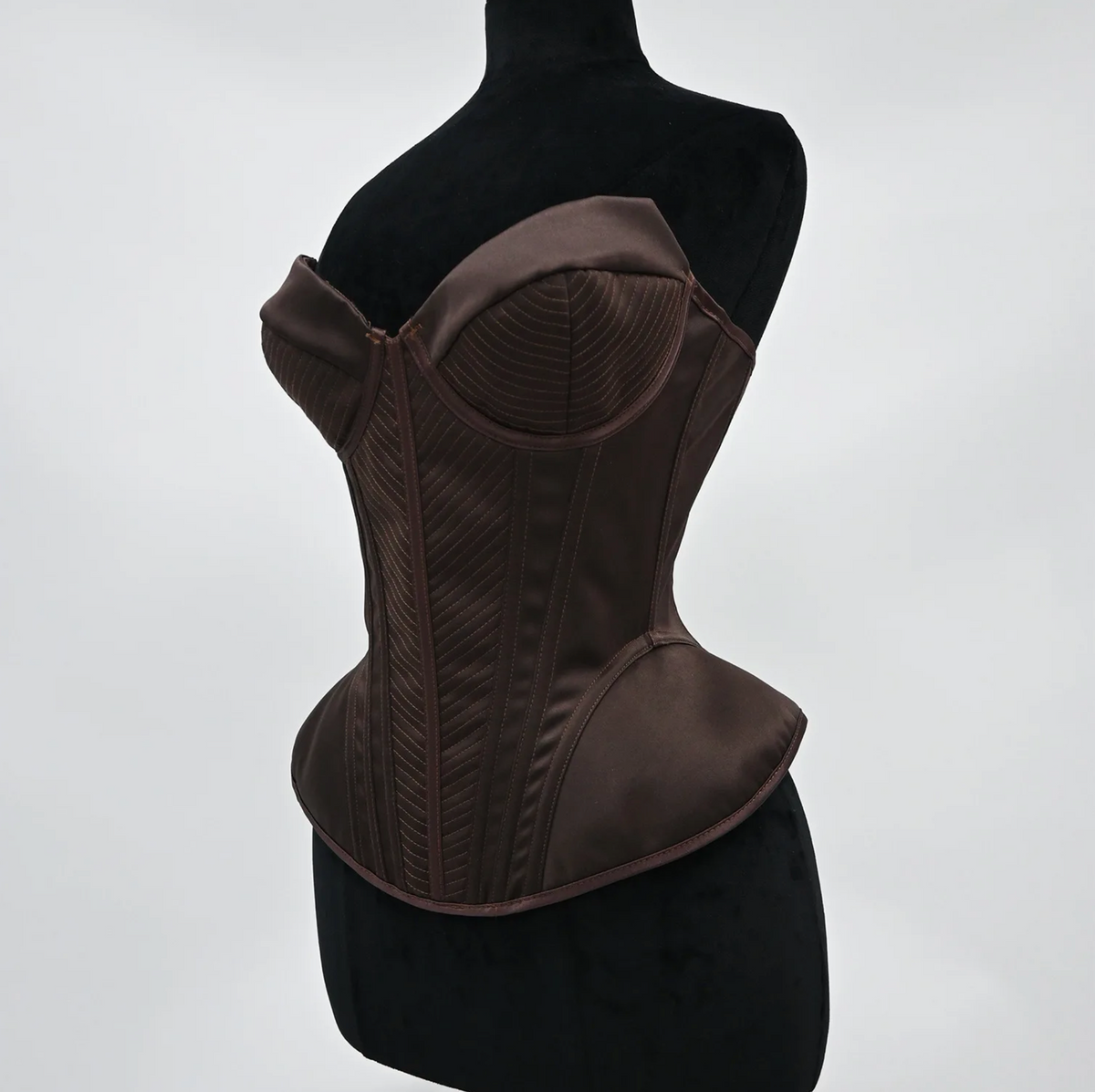 Structured dark brown satin corset bustier with intricate stitched paneling and a sculpted, vintage-inspired silhouette.