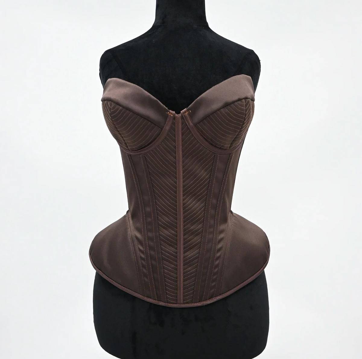 Structured dark brown satin corset bustier with intricate chevron stitching and a sculpted, vintage-inspired silhouette.