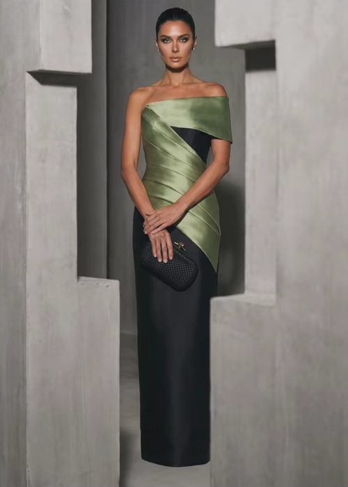 Model in a structured olive green and black satin twill floor-length gown with an asymmetrical off-shoulder neckline.