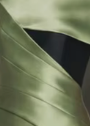 Close-up of the Faustini gown in sage green satin twill featuring a bold black contrast panel and structured pleating.