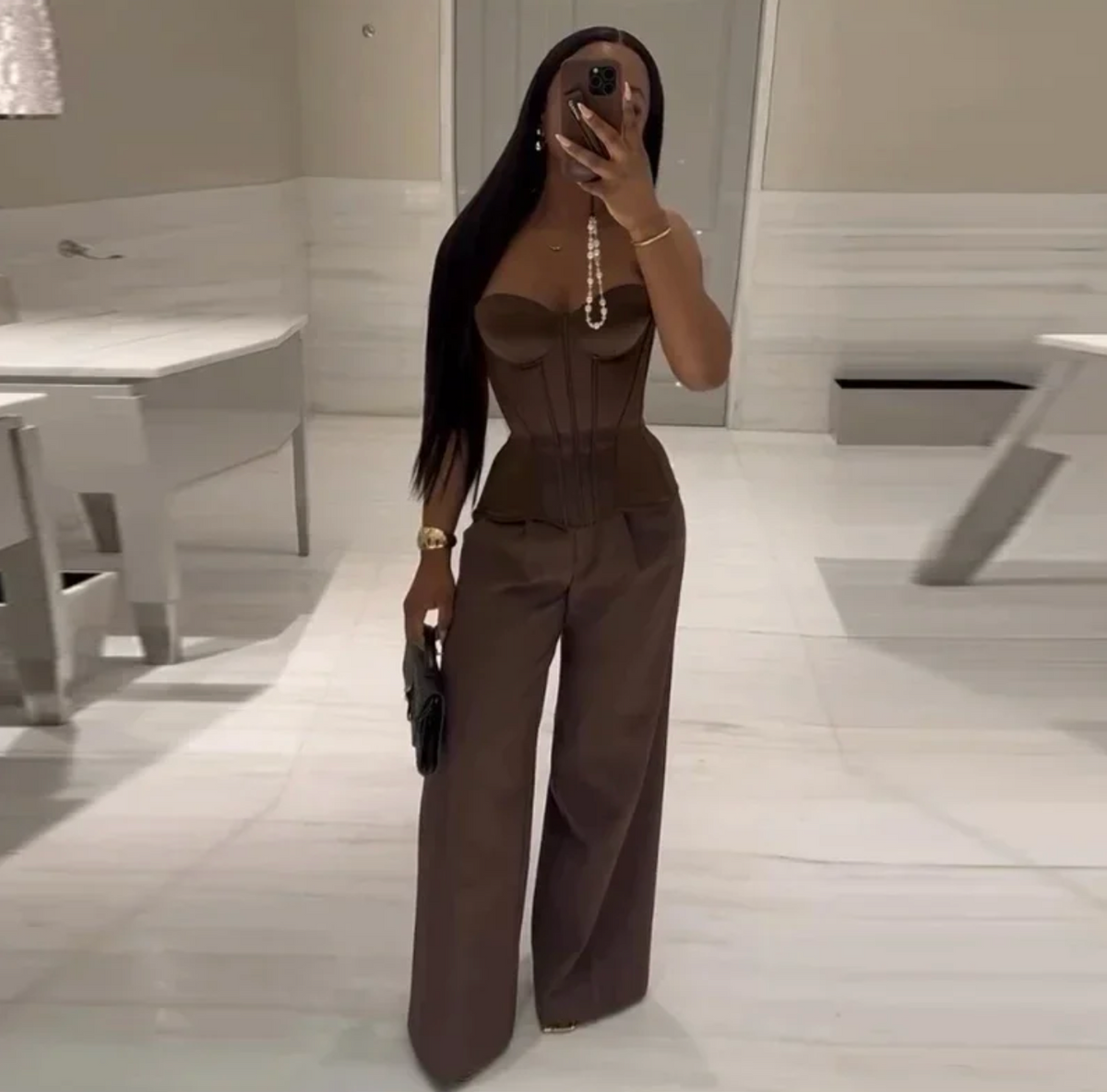 Woman wearing a dark brown strapless bandage corset top with a structured, cinched waist and matching wide-leg trousers.