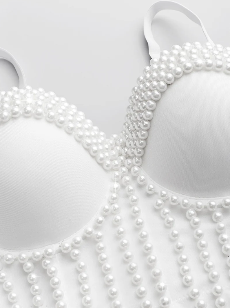White Ina corset camisole featuring intricate pearl bead embellishments and decorative fringe detailing.
