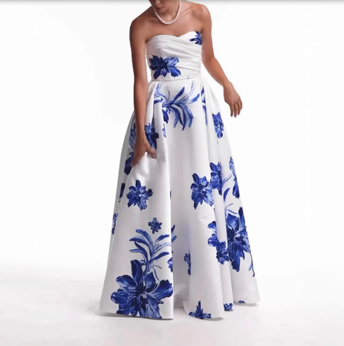 Woman wearing the Valjean Ave Maxi strapless white gown with blue floral patterns on a white background