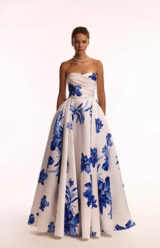 Woman wearing the Valjean Ave Maxi strapless white gown with blue floral patterns on a white background