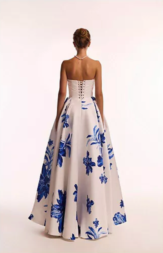 Woman wearing the Valjean Ave Maxi strapless white gown with blue floral patterns on a white background